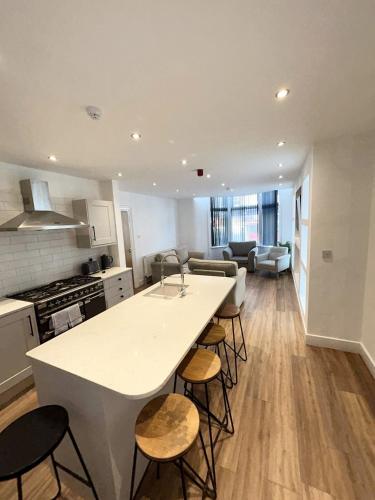 a kitchen and living room with a counter and chairs at Beach House By Sasco in Blackpool