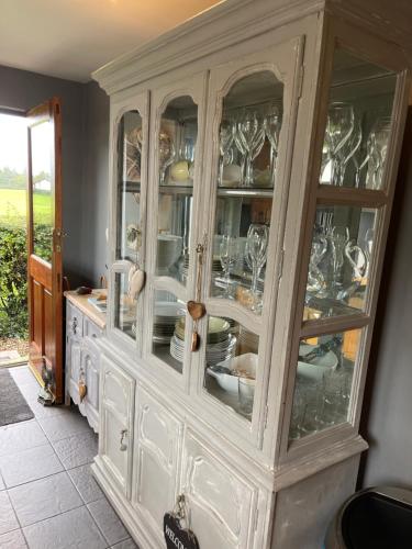 a white cabinet with glass doors with dishes in it at Woodend Cottage in Dumfries