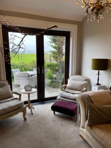 a living room with chairs and a large sliding glass door at Woodend Cottage in Dumfries