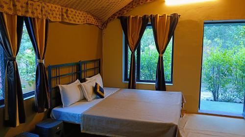 um quarto com uma cama e 2 janelas em Ranthambhore Tiger Valley em Sawai Madhopur