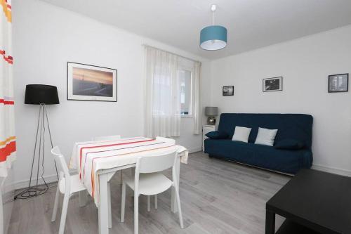 ein Wohnzimmer mit einem Tisch und einem blauen Sofa in der Unterkunft Le Bon Repos - Séjours professionnels et vacances en famille aux portes de Paris in Garches