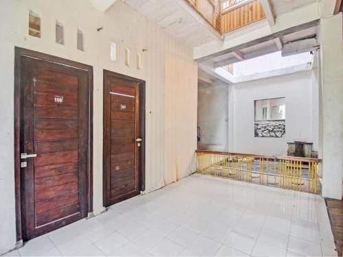an empty room with two wooden doors and a balcony at OYO 92964 Kost 99 in Manado