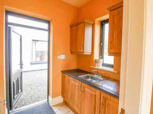 an orange kitchen with a sink and a window at Ocean View in Adrigole