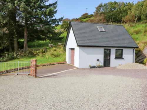 a small white garage with a dog sitting in the doorway at Ocean View in Adrigole