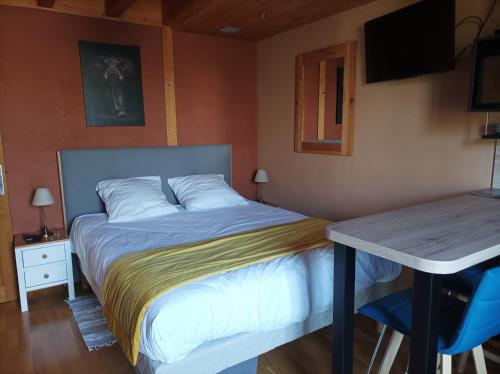a bedroom with a bed and a table and a desk at Un petit coin de paradis in Orpierre
