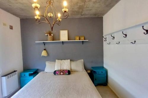 a bedroom with a bed and a chandelier at Moderno dpto cercanías Puerto de Frutos! in Tigre