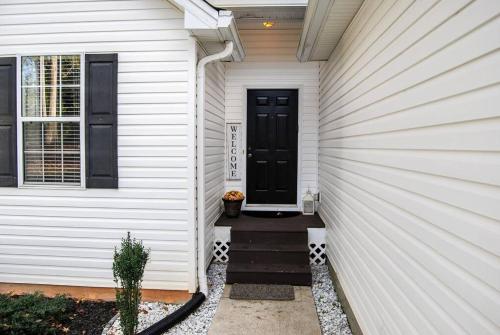 a white house with a black door and stairs at At Home by Mall of GA! in Buford