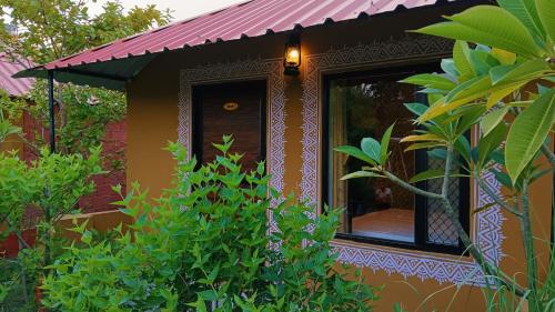 a small house with a red roof in a garden at Ranthambhore Tiger Valley in Sawāi Mādhopur
