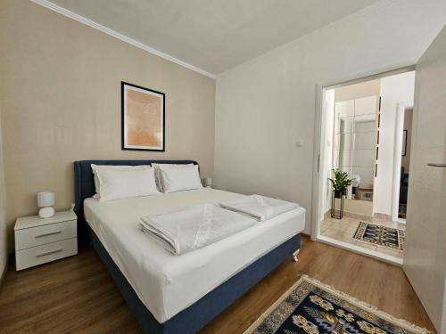 a bedroom with a large white bed and a mirror at BLUE APARTMENT MOSTAR in Mostar