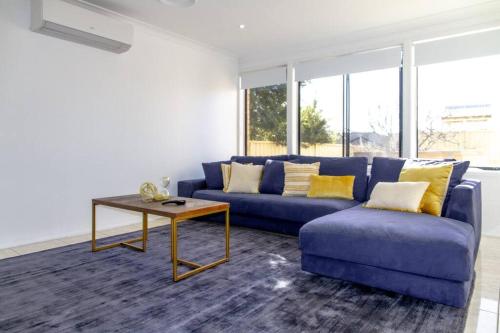 a living room with a blue couch and a table at Sunny & Spacious Family Retreat in Prestons