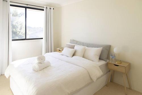 a white bedroom with a white bed with a window at Sunny & Spacious Family Retreat in Prestons