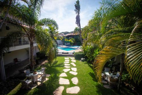 un jardín con palmeras y una piscina en Armação dos Búzios Pousada Design, en Búzios