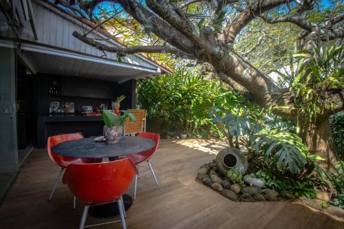 un patio con mesa y sillas bajo un árbol en Armação dos Búzios Pousada Design en Búzios