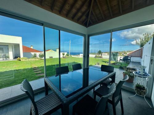 eine abgeschirmte Veranda mit einem Glastisch und Stühlen in der Unterkunft Serenity Azores - Casa da Aldeia in Nordestinho