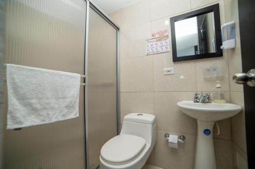 La salle de bains est pourvue de toilettes, d'un lavabo et d'un miroir. dans l'établissement Parque del Cafe Apartamento! Piscinas, Parqueadero, WiFi, Netflix., à Montenegro