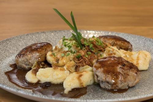 a plate of food with meatballs and potatoes on a table at Boutique-Hotel Vincenz in Brigels