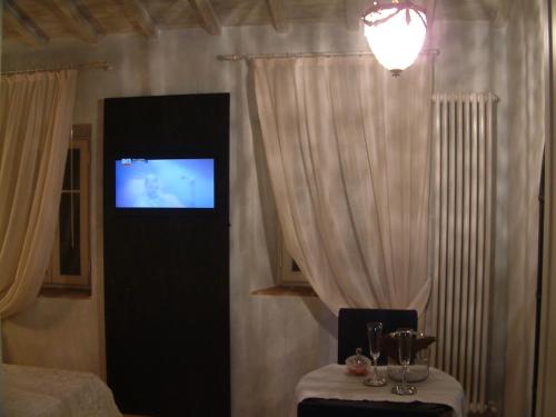 a room with a television and a table with glasses at La Casa della Peggiola - Le Case Antiche in Verucchio