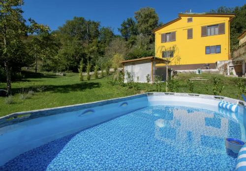 B&B Naturista e Spa Mondoselvaggio في لوكّا: حمام سباحة في ساحة مع منزل أصفر في الخلفية