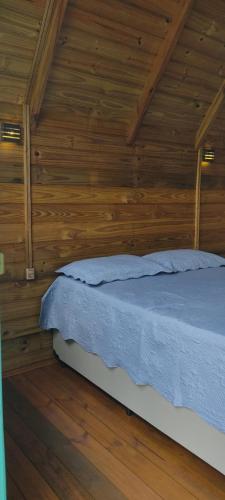um quarto com uma cama numa parede de madeira em Chácara do sossego em Passa Quatro