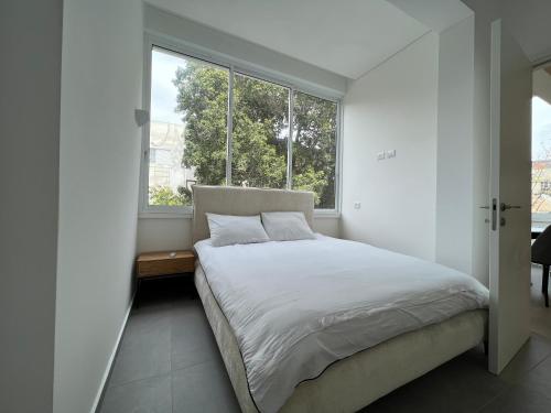 a bedroom with a bed and a large window at Smolenskin 3 Bedrooms Apartment in Tel Aviv