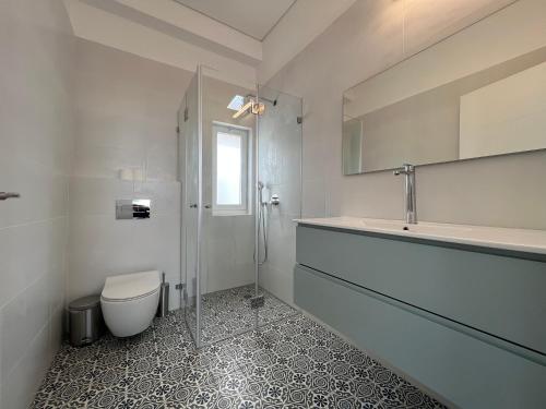 a white bathroom with a toilet and a sink at Smolenskin 3 Bedrooms Apartment in Tel Aviv