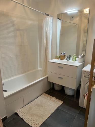 W łazience znajduje się biała wanna, umywalka i lustro. w obiekcie Chez moi à côté du Groupama stadium w mieście Décines-Charpieu