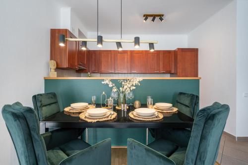 Prime Location Apartment في بودابست: غرفة طعام مع طاولة سوداء وكراسي خضراء