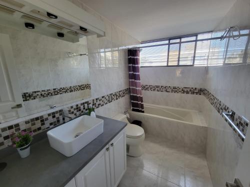 een badkamer met een wastafel, een bad en een toilet bij BELLAVISTA REST in Quito