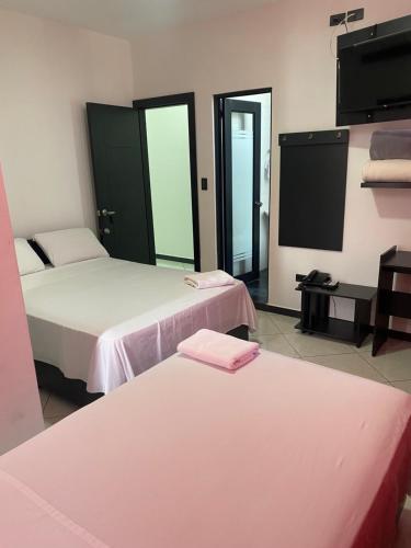 a room with two beds and a flat screen tv at BRYSS HOTEL in Santo Domingo de los Colorados