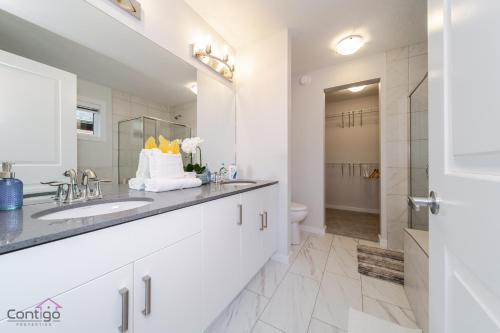 a white bathroom with a sink and a toilet at Orchards Retreat, AC, Family Friendly, Sleeps 10, NearAirprt in Nisku