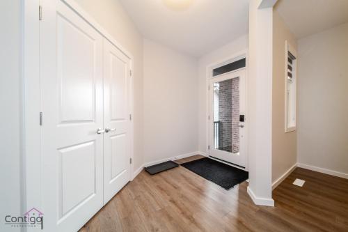 an empty hallway with a white door and wood floors at Orchards Retreat, AC, Family Friendly, Sleeps 10, NearAirprt in Nisku