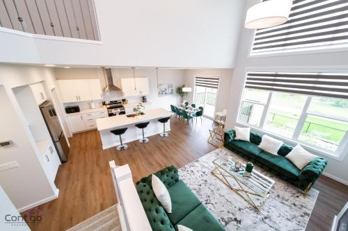a living room with a green couch and a kitchen at Orchards Retreat, AC, Family Friendly, Sleeps 10, NearAirprt in Nisku