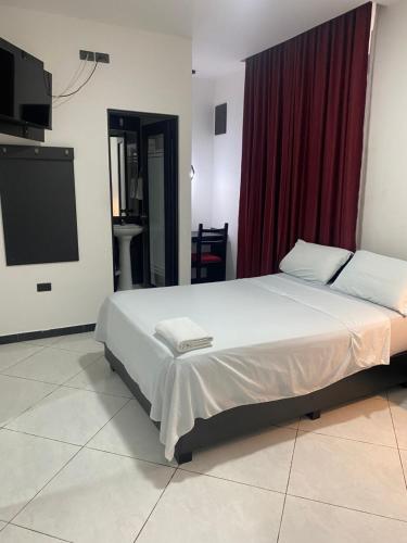a bedroom with a large bed and a flat screen tv at BRYSS HOTEL in Santo Domingo de los Colorados