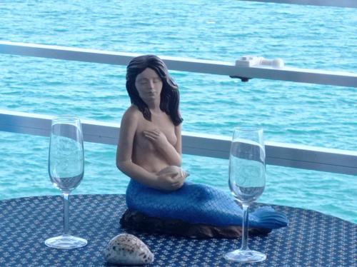 a statue of a woman sitting on a table with two wine glasses at apartamento junto al mar in Cullera