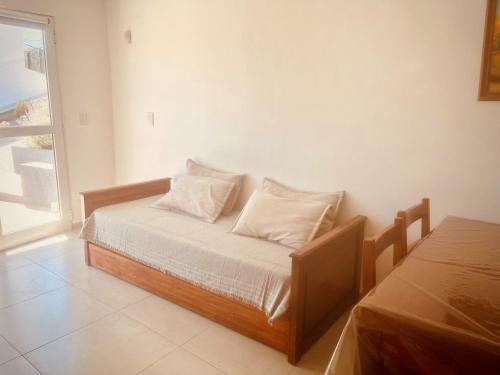 1 dormitorio con 1 cama con sábanas blancas y ventana en Depto en la Sierra!! Increible vista en Villa Carlos Paz