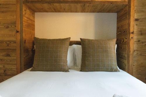 a bed with a wooden headboard and two pillows at Apartment Dario in Verbier