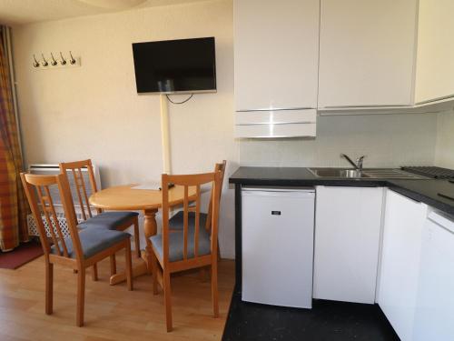 une cuisine avec une table, des chaises et un évier dans l'établissement Studio cosy avec balcon, proche pistes et commerces, 4 pers, WiFi, animaux acceptés - FR-1-502-535, à Tignes