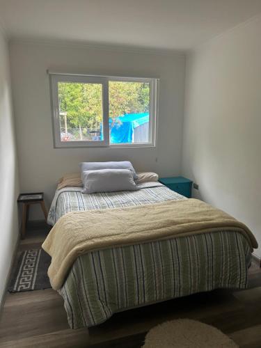 Bett in einem Schlafzimmer mit Fenster in der Unterkunft Casa En medio del Bosque in Puerto Varas