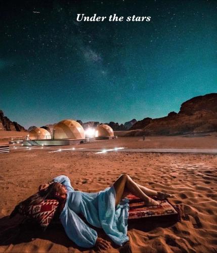 a man laying on a beach under the stars at RUM WORLD BUBBLE lUXURY CAMP in Wadi Rum