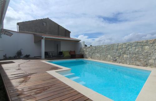 a swimming pool with a wooden deck next to a building at Solar das Estrelas in Fátima