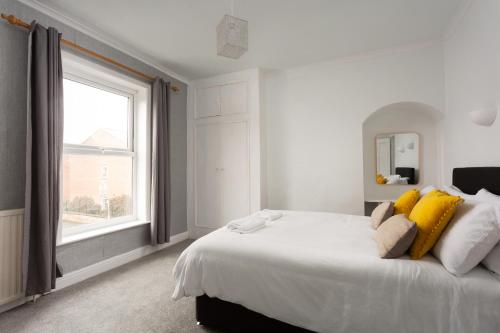 - une chambre blanche avec un grand lit et des oreillers jaunes dans l'établissement Lovely city town house with parking sleeps 2-6 people, à York