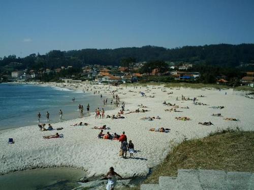 a group of people on a beach near the water at Hotel Xeito in Combarro