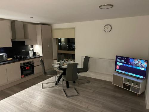 a kitchen and a dining room with a table and a television at Kensington House by Solitaire Suites in Slough