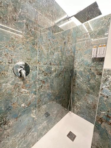 La salle de bains est pourvue d'une douche et d'un mur en pierre. dans l'établissement CARMA SUITE, à Naples