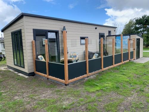 a smallshed with a row of windows in a yard at Chalet2rent Ameland in Ballum