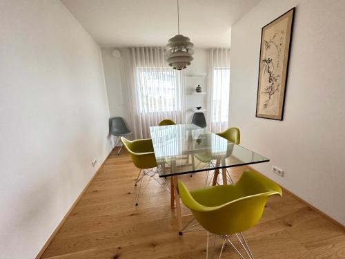 a dining room with a glass table and green chairs at Apartment in Austurkór- Birta Rentals in Reykjavík