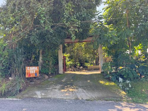 an entrance to a forest with a sign in the middle at El mangal B&B in Suchitoto