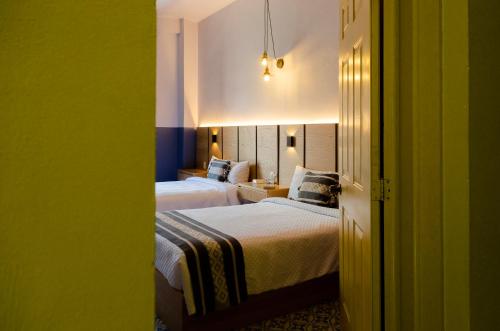 two beds in a hotel room with green walls at Hotel Casona Oaxaca in Oaxaca City