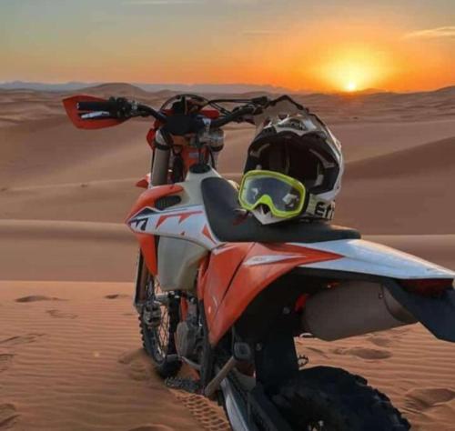 a motorcycle parked in the sand in the desert at Sahara Camp Light in Mhamid