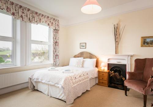 a bedroom with a bed and a chair and a fireplace at Knowles in Colyton